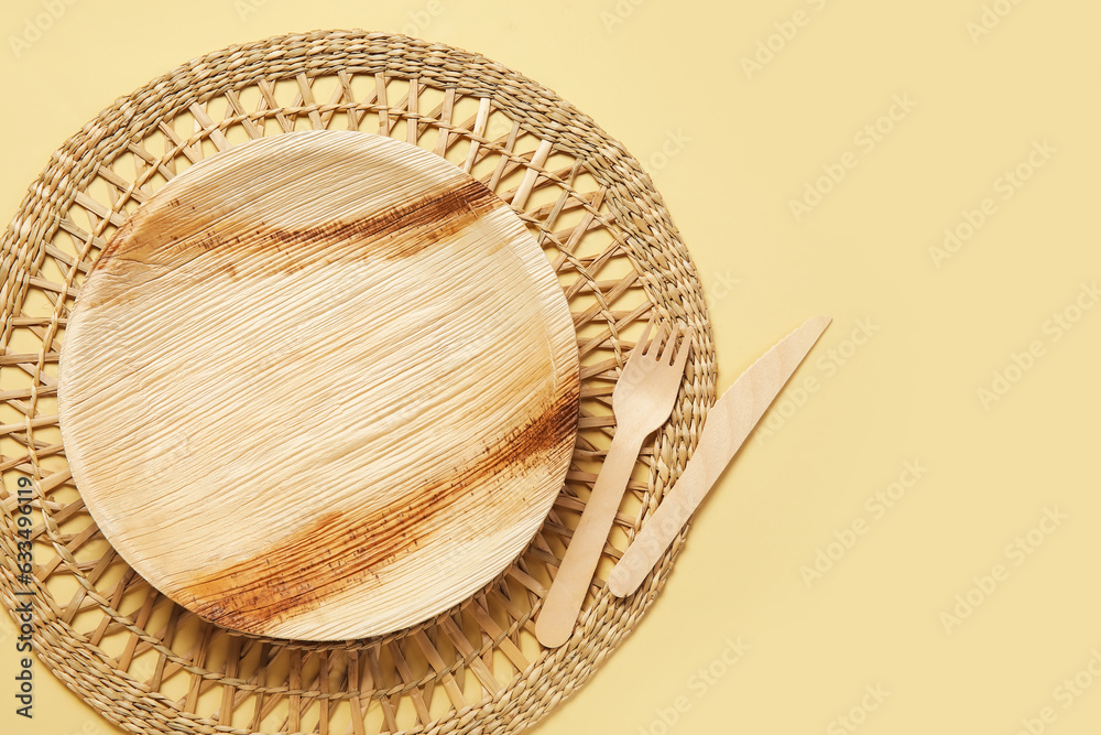 Wooden plate, cutlery and wicker mat on beige background