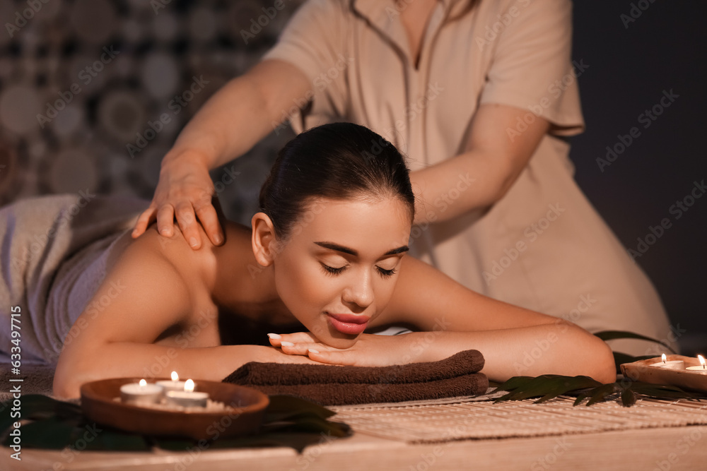 Pretty young woman having massage in spa salon