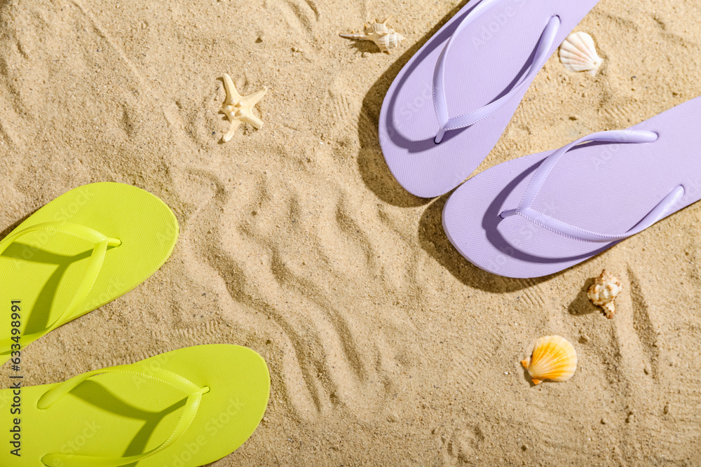 Frame made of colorful pairs of flip flops on sandy background