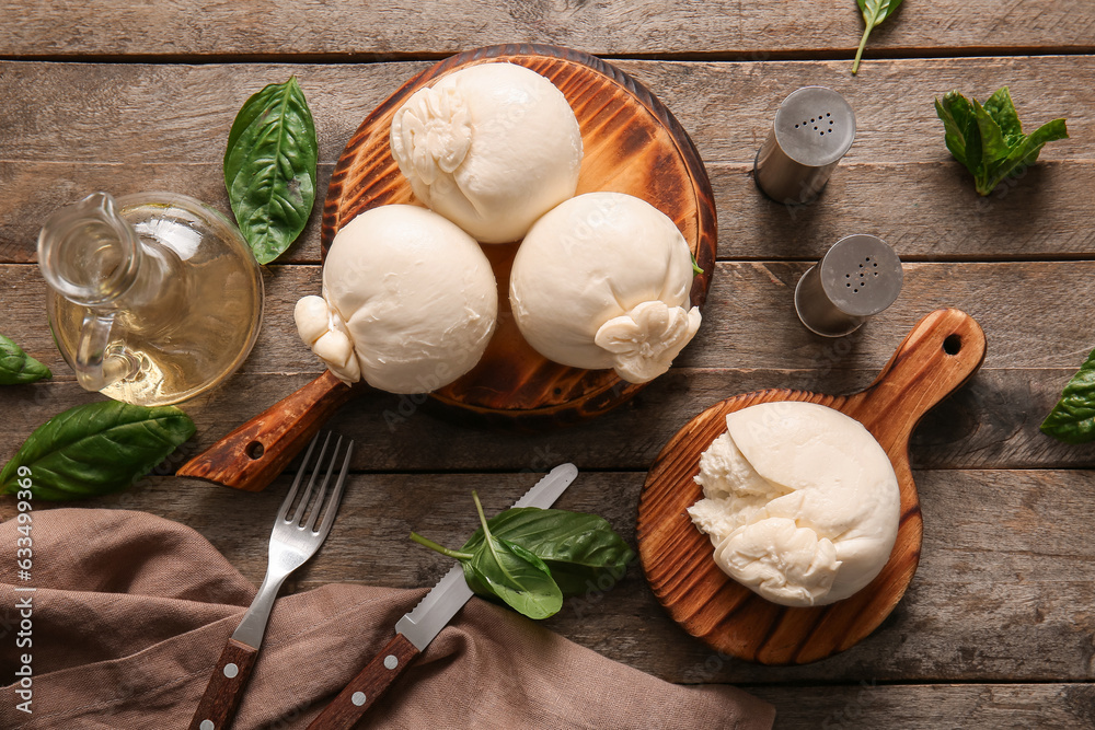 Boards of tasty Burrata cheese with basil on wooden background