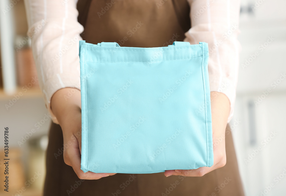 Mother with lunch box bag for school in kitchen