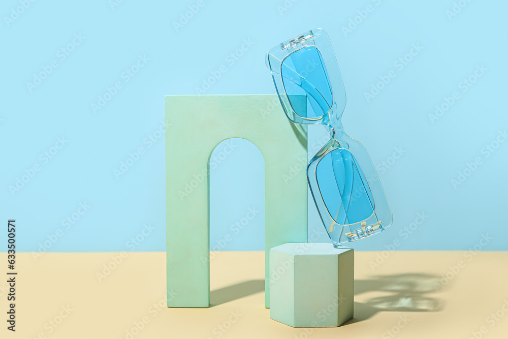 Decorative podiums with stylish sunglasses on yellow table