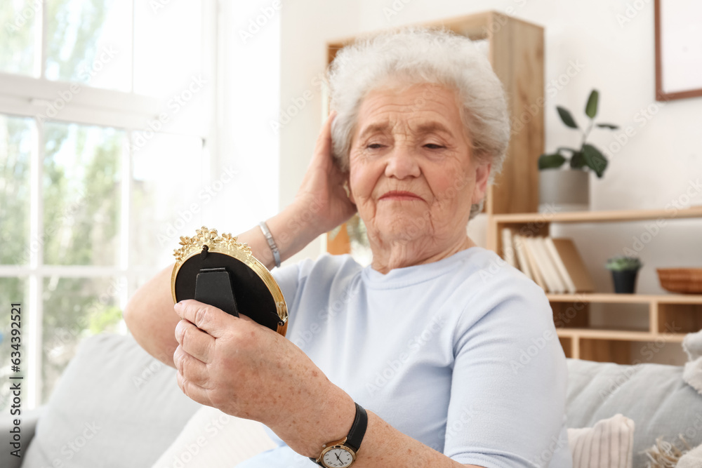 Senior woman with mirror at home, closeup