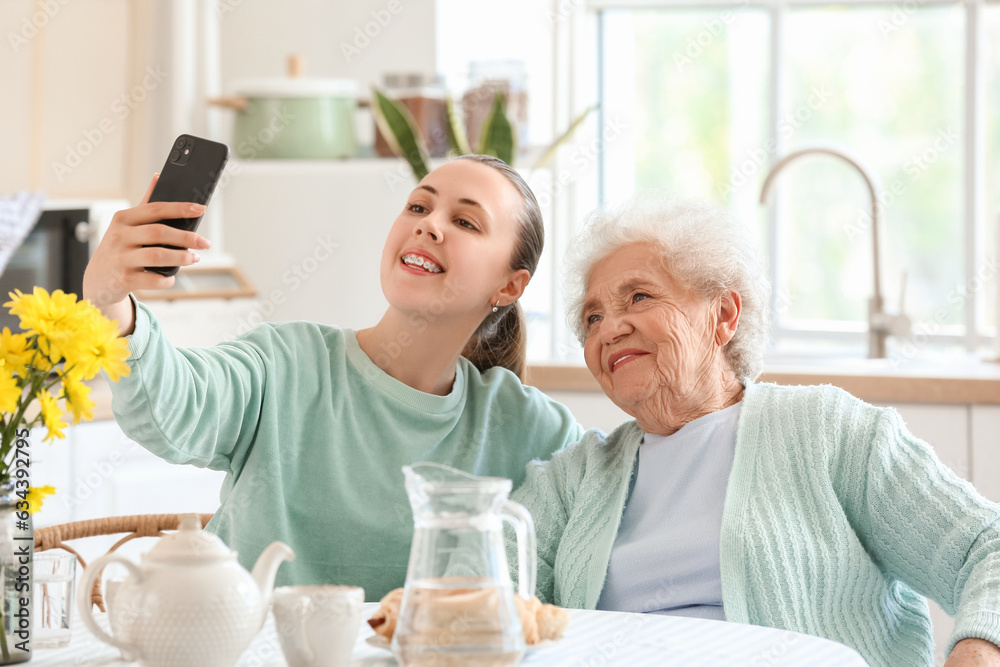 Senior woman with her granddaughter taking selfie in kitchen