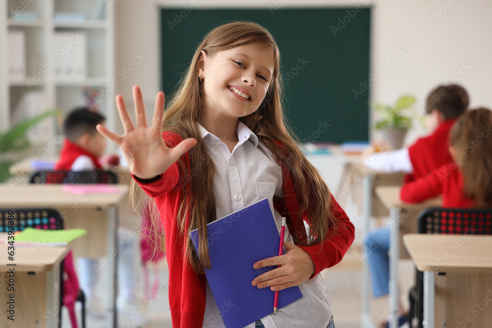 Little schoolgirl with copybook in classroom