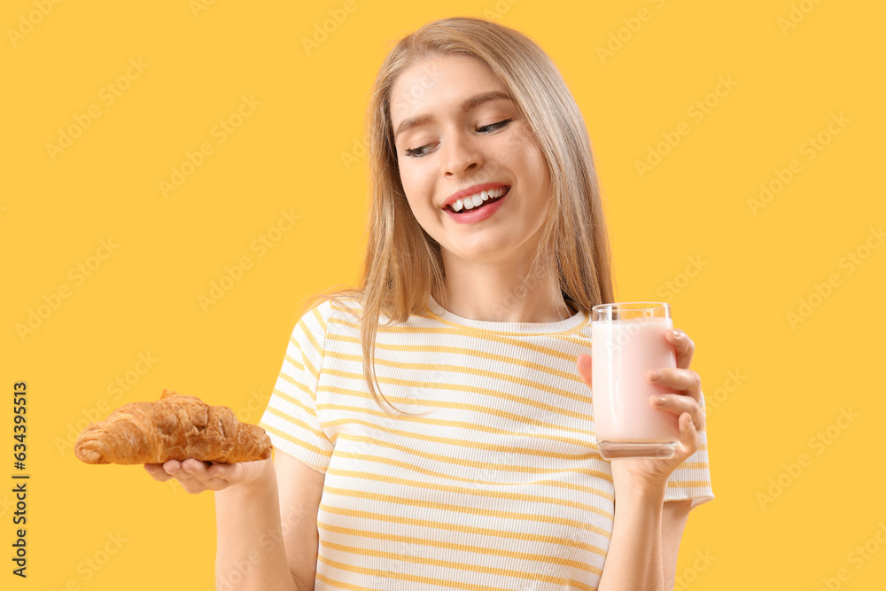 Young woman with tasty croissant and yoghurt on yellow background