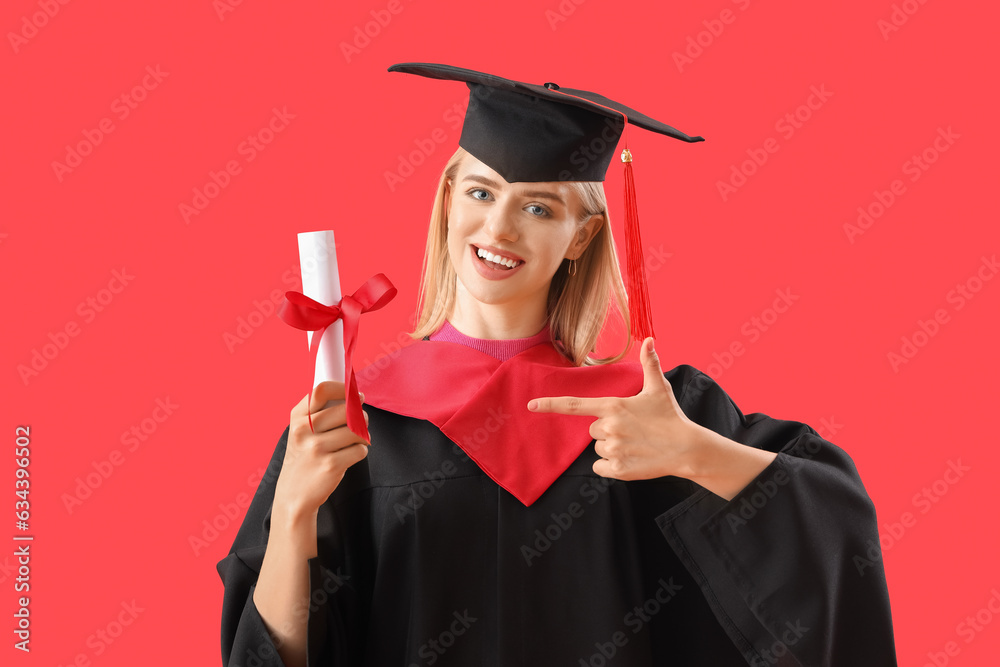 Female graduate student pointing at diploma on red background