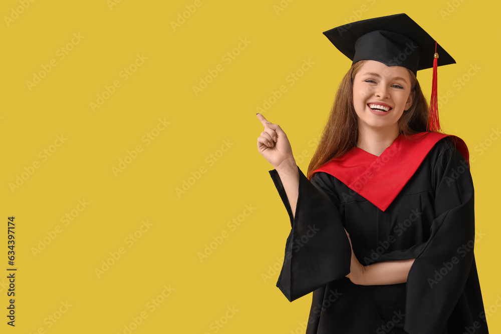 Female graduate student pointing at something on yellow background