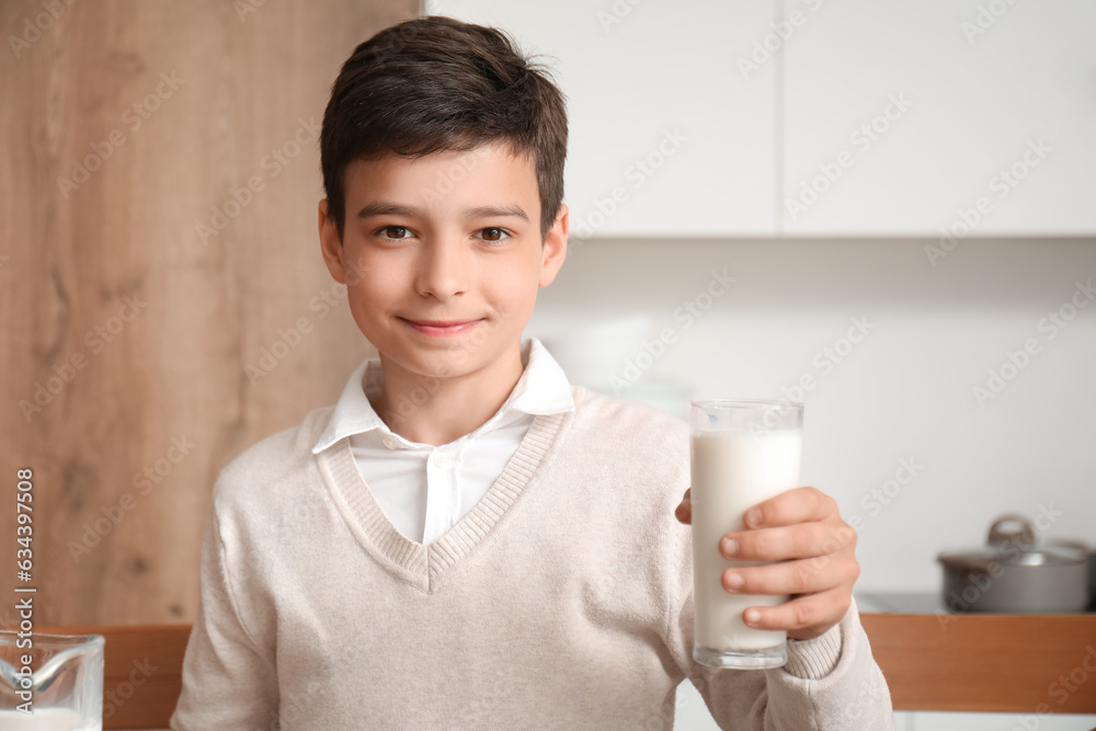 Little boy with glass of milk in kitchen, closeup