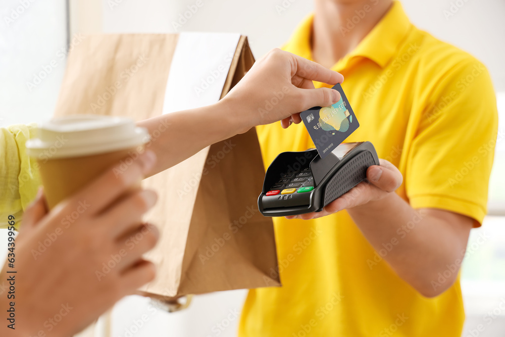 Young courier receiving payment for food from woman at doorway, closeup