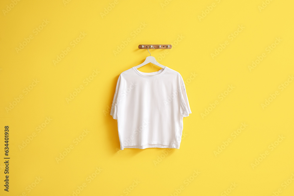 Stylish white t-shirt hanging on yellow background