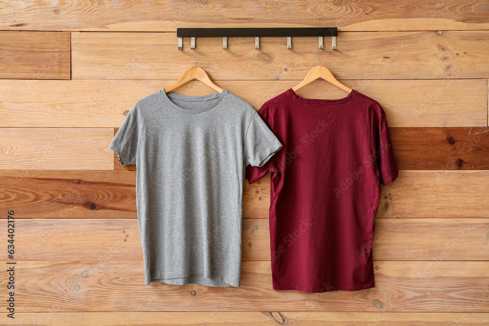 Stylish t-shirts hanging on wooden background