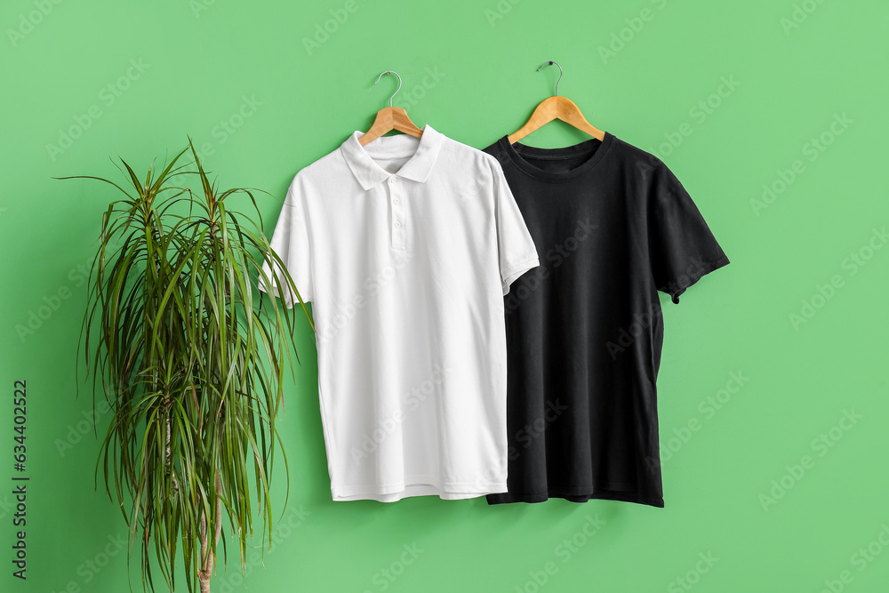 Stylish t-shirts hanging on green background