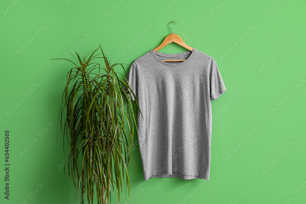 Stylish grey t-shirt hanging on green background