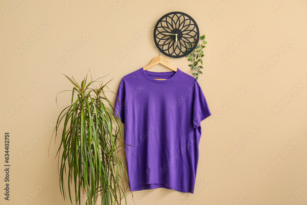 Stylish purple t-shirt hanging on beige background