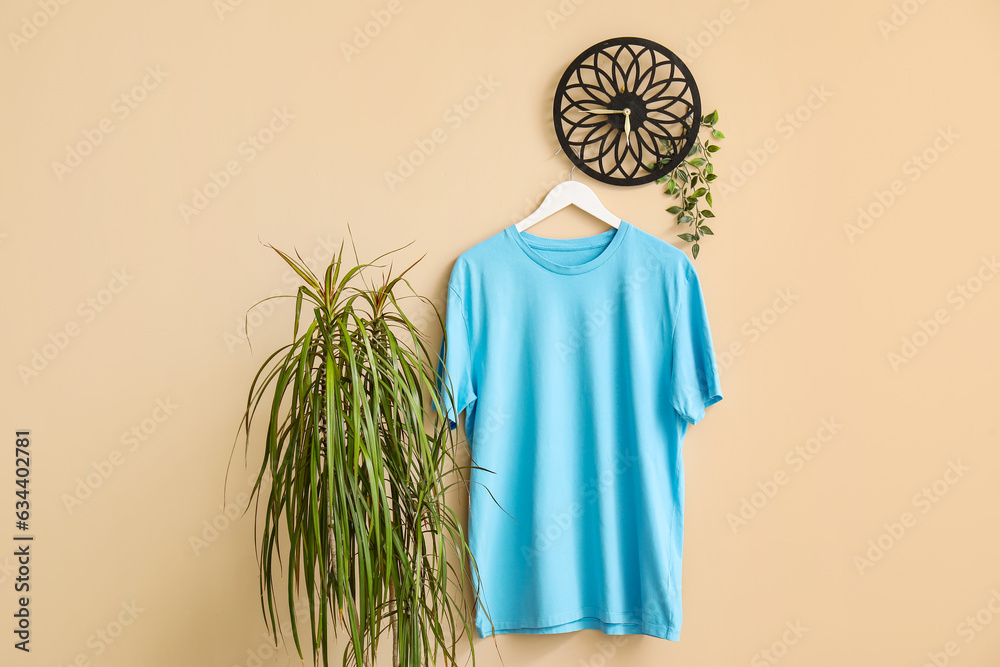 Stylish blue t-shirt hanging on beige background