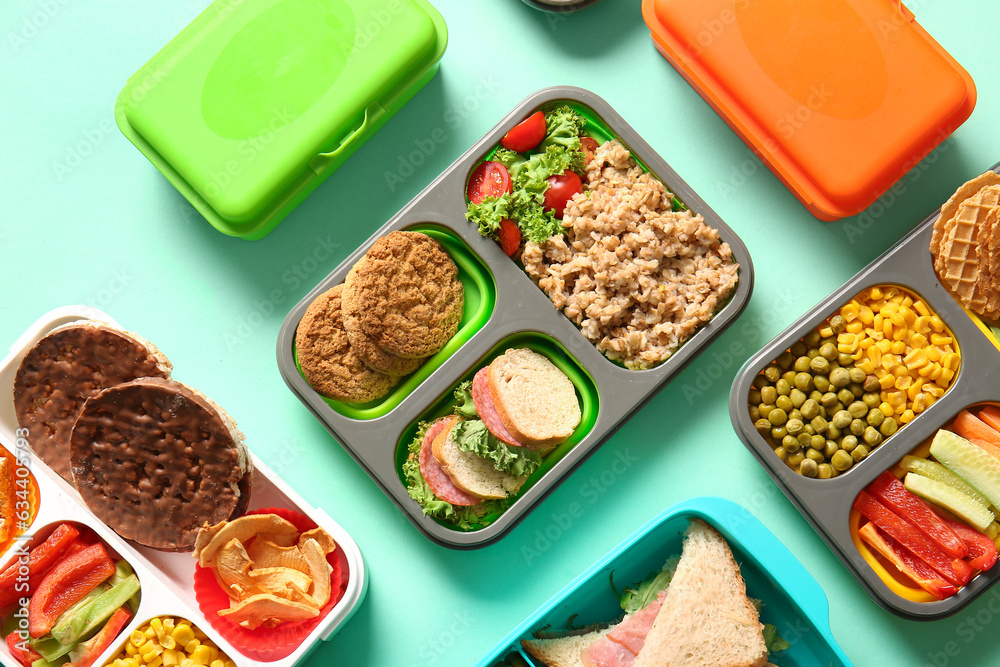 Many lunchboxes with different delicious food on turquoise background