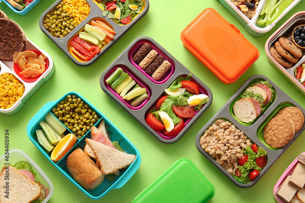 Many lunchboxes with different delicious food on green background