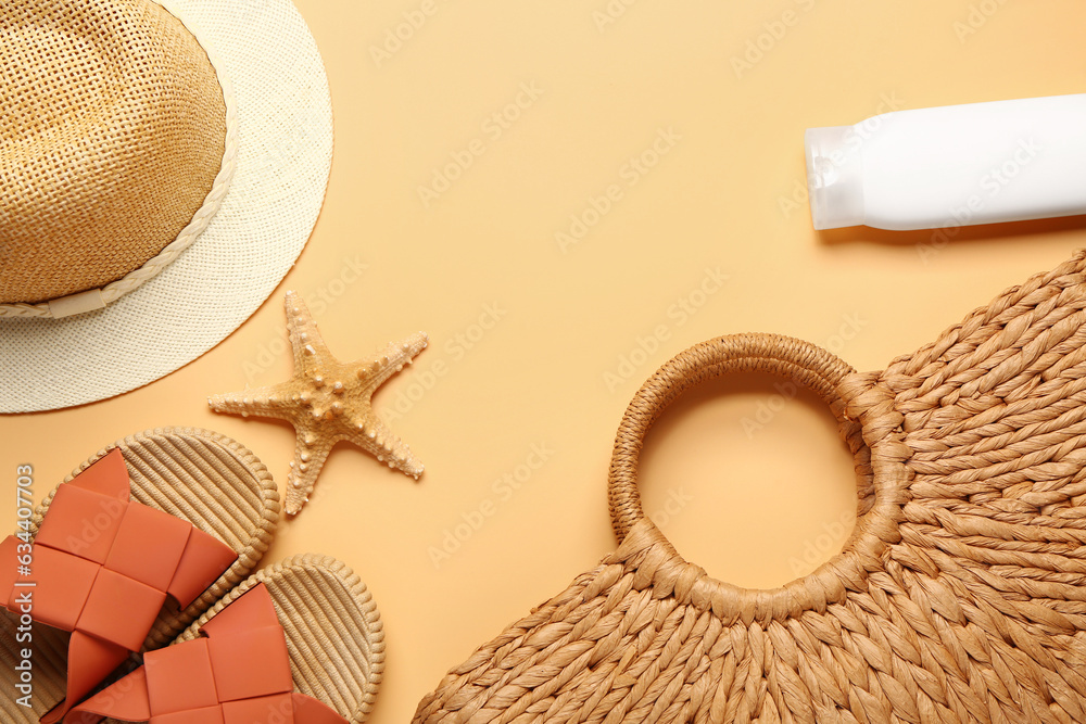 Bottle of sunscreen cream with beach accessories on orange background