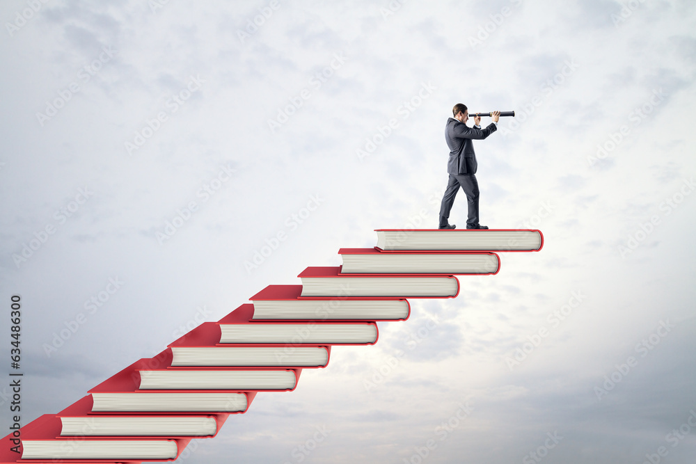 Side view of young businessman with telescope on red book steps. Cloudy sky background with mock up 