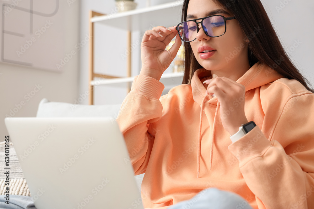 Young woman with laptop wearing glasses at home