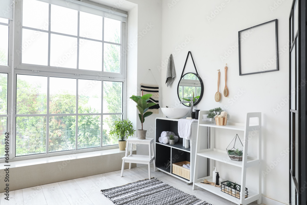 Interior of light bathroom with sink bowl, bath accessories and shelving units