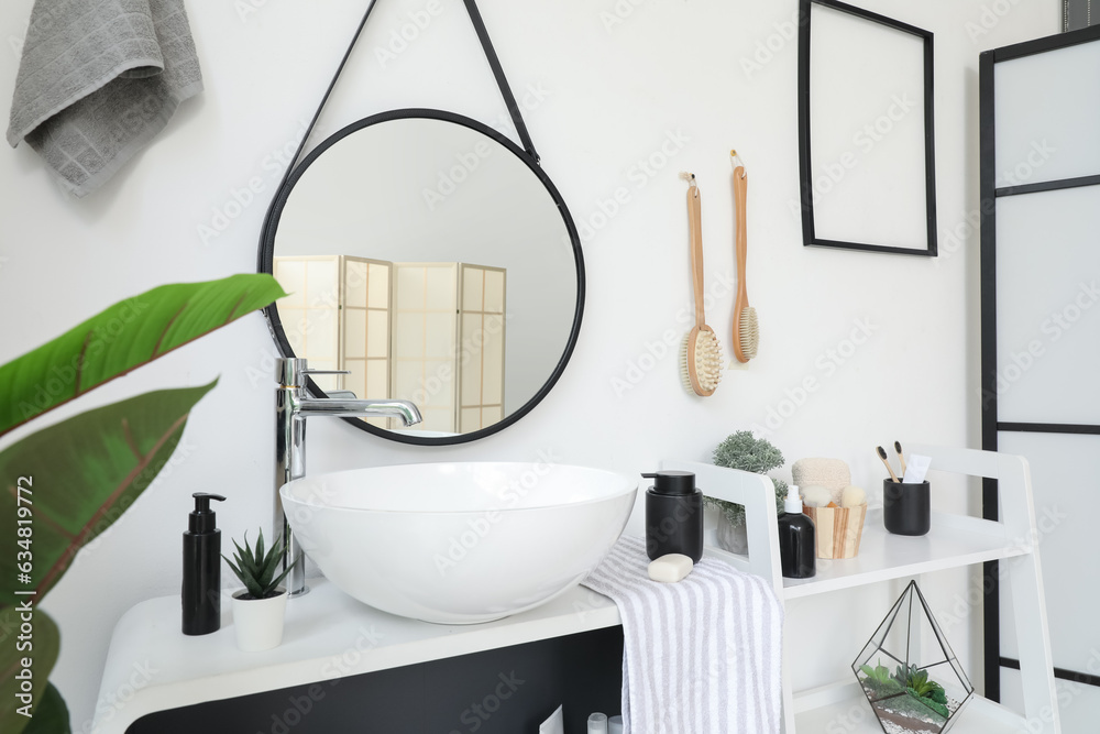 Sink bowl and bath accessories on shelving unit in light bathroom