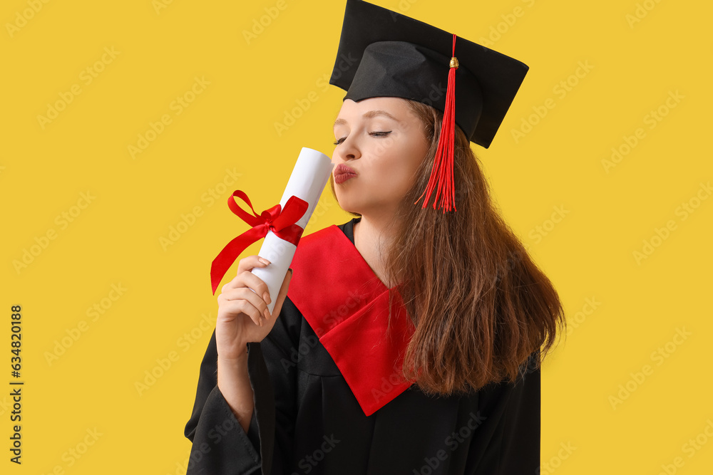 Female graduate student with diploma blowing kiss on yellow background