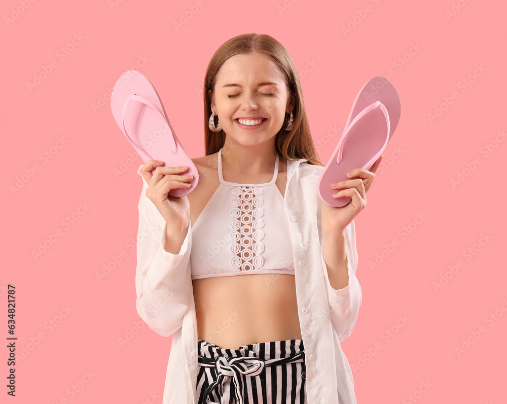 Funny young woman with flip-flops on pink background