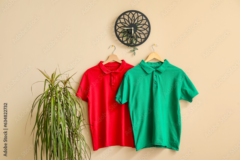 Stylish t-shirts hanging on beige background