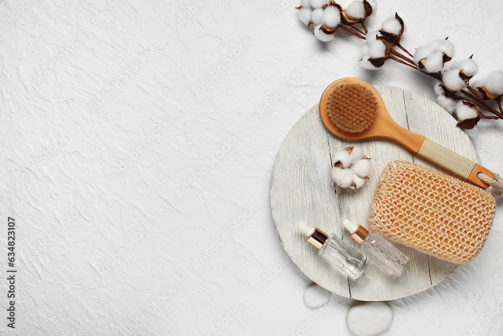 Composition with bottles of essential oil, bath supplies and cotton branch on light background