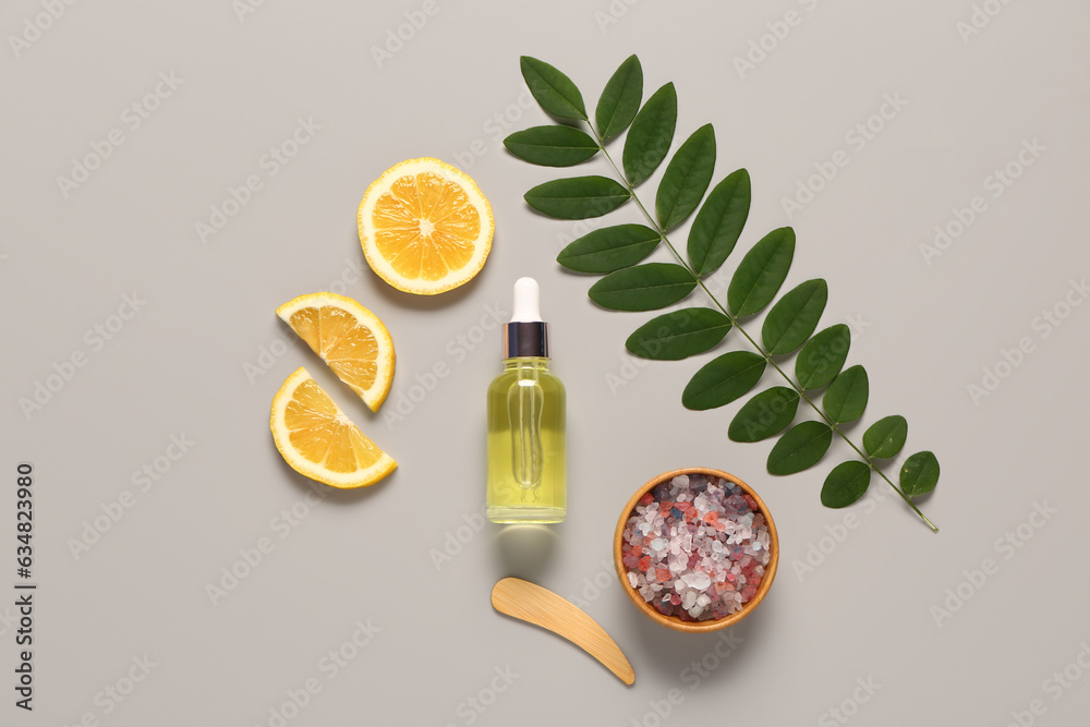 Bottle of cosmetic oil with lemon and sea salt on grey background