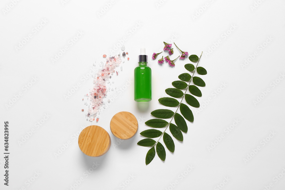 Bottle and jars of cosmetic products with sea salt on white background