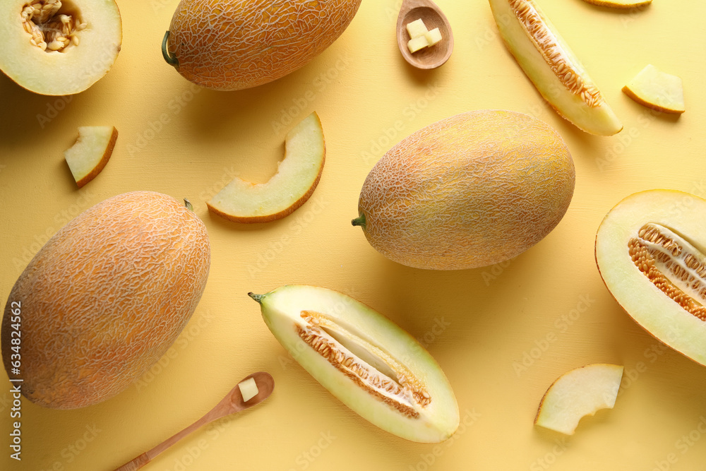 Sweet melons and wooden spoons with pieces on yellow background