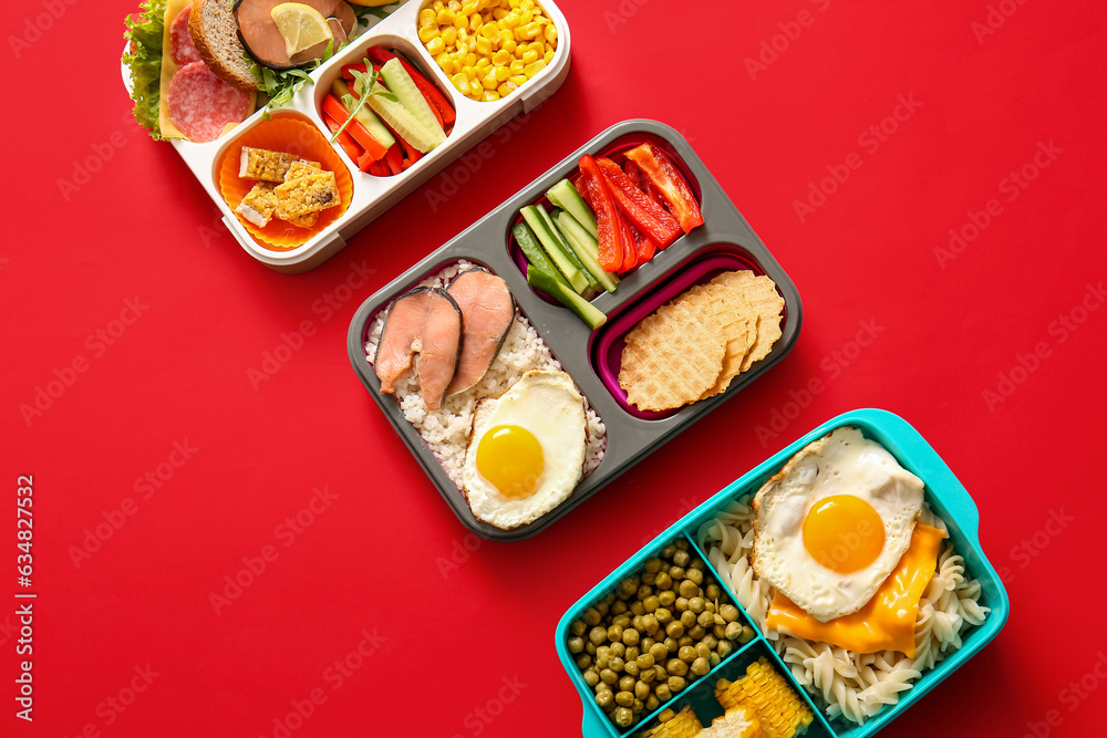 Lunchboxes with different delicious food on red background