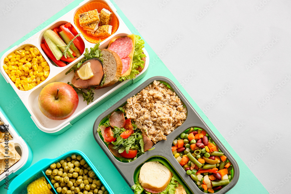 Lunchboxes with different delicious food on color background