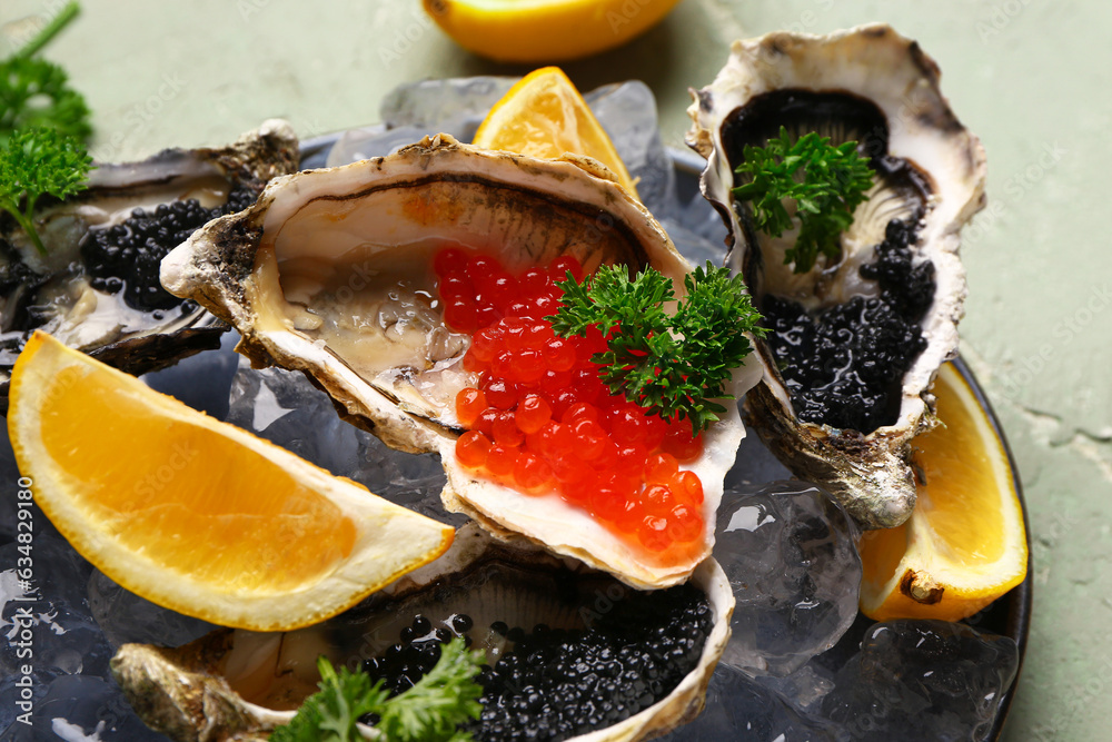 Plate of tasty oysters with lemon, black and red caviar on grey background