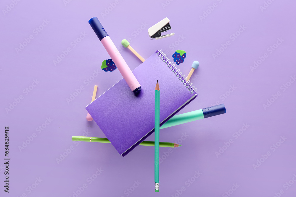 Different flying stationery on lilac background