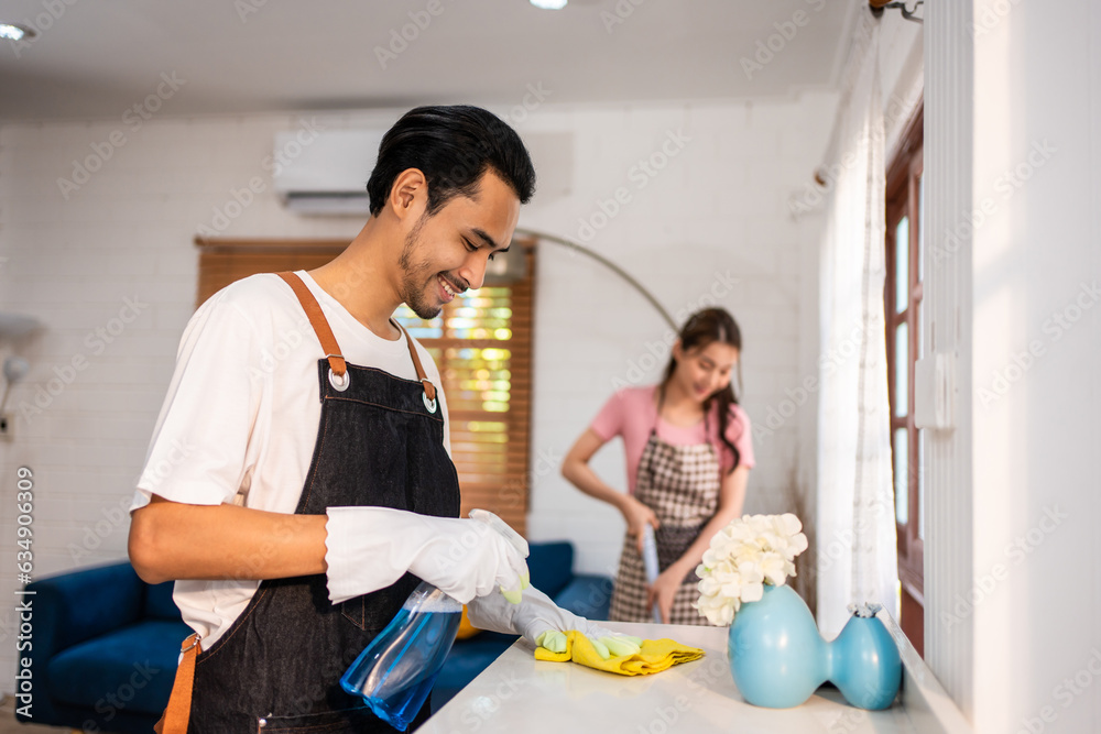 Asian attractive young man and woman cleaning house indoors together. 