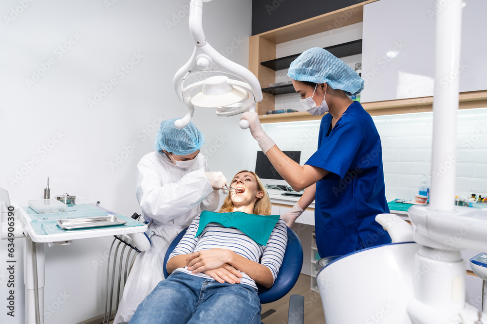 Female dentist examine tooth to Caucasian girl at dental health clinic. 