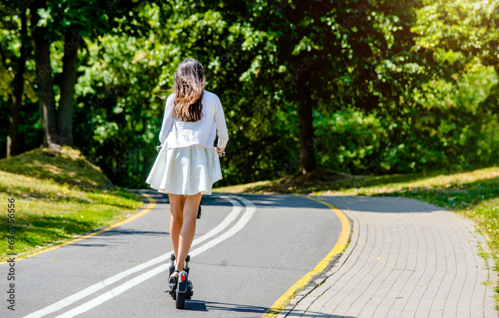 Girl rides an electric scooter in the summer Park 