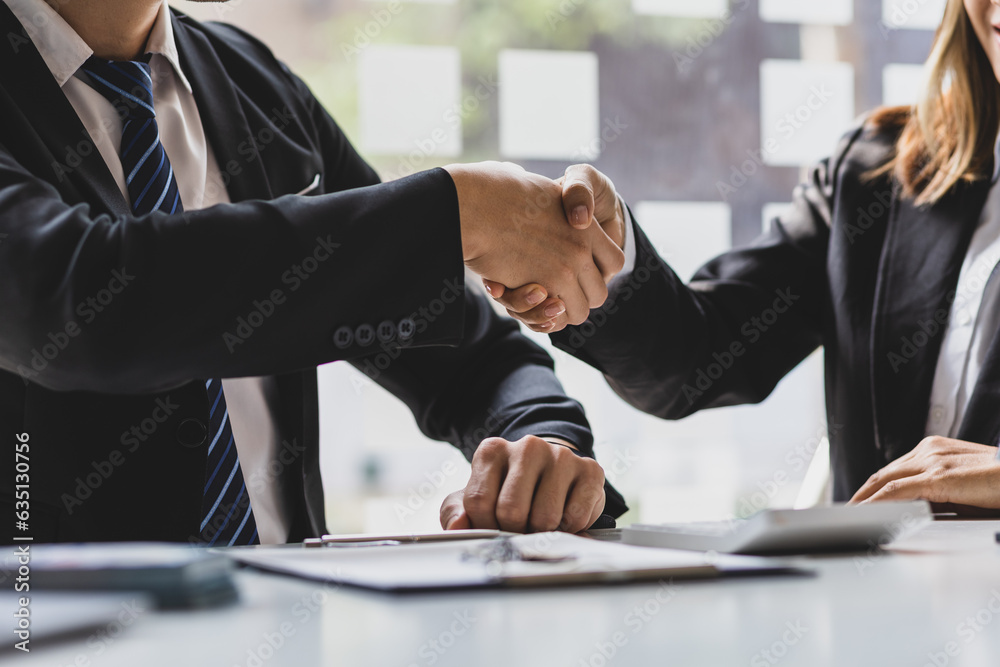 Business people shake hands with colleagues at a meeting.