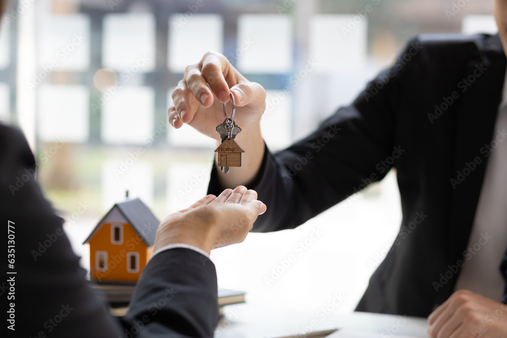 Real estate agent hands over the house keys to a homebuyer after the purchase agreement has been sig