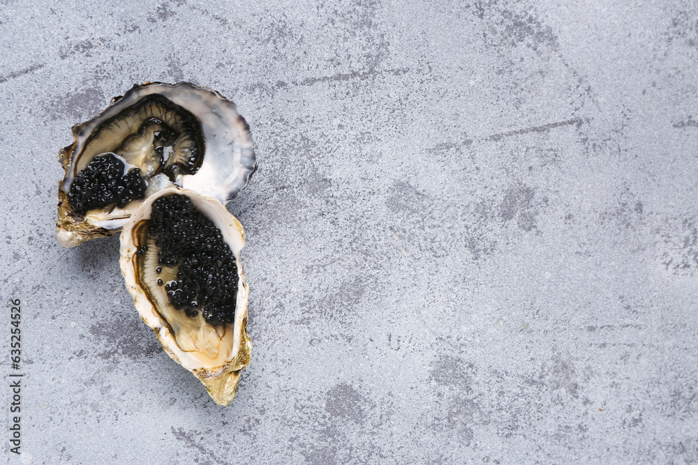 Tasty oysters with black caviar on grey background