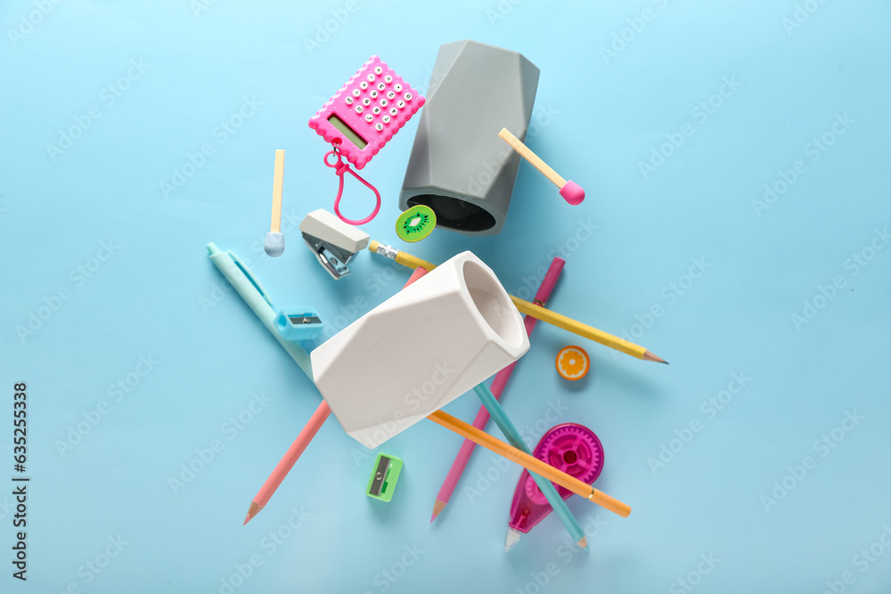 Different stationery and holders flying on color background