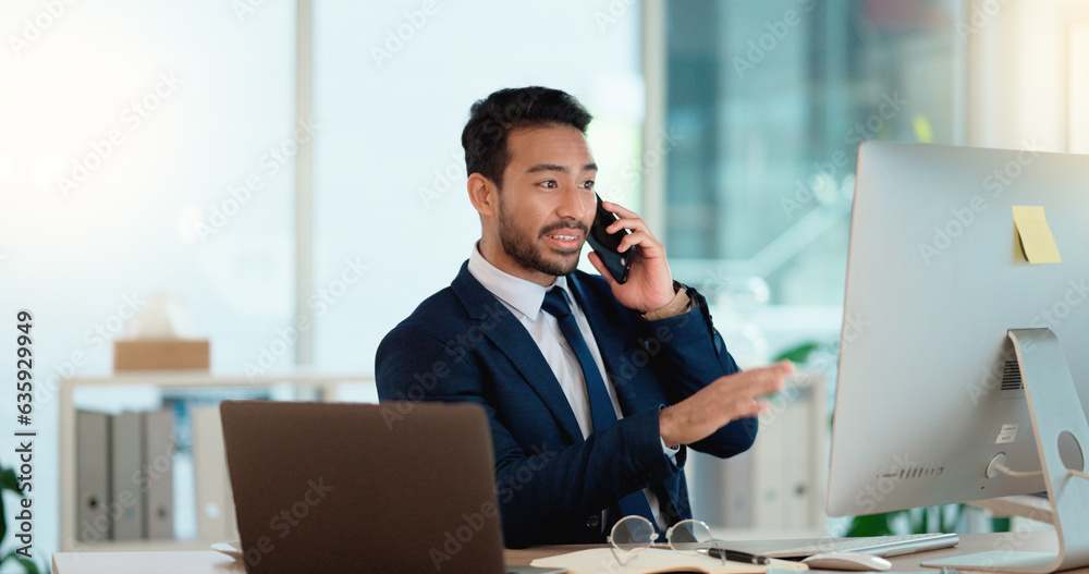 Happy business man talking on his phone while working on a computer and smiling alone at work. Young