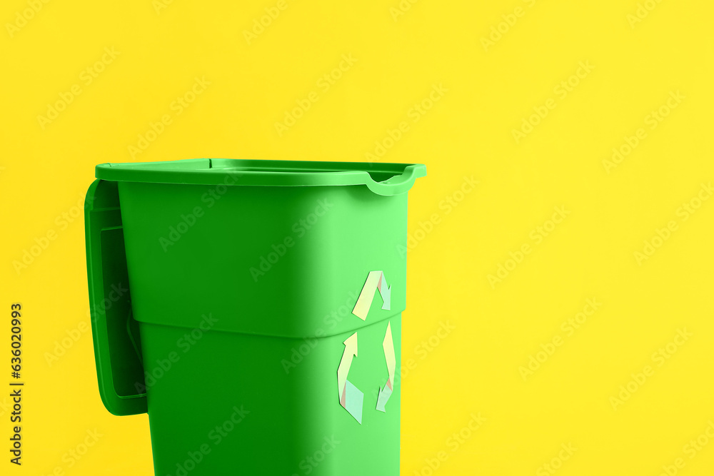 Green container for garbage on yellow background. Recycling concept