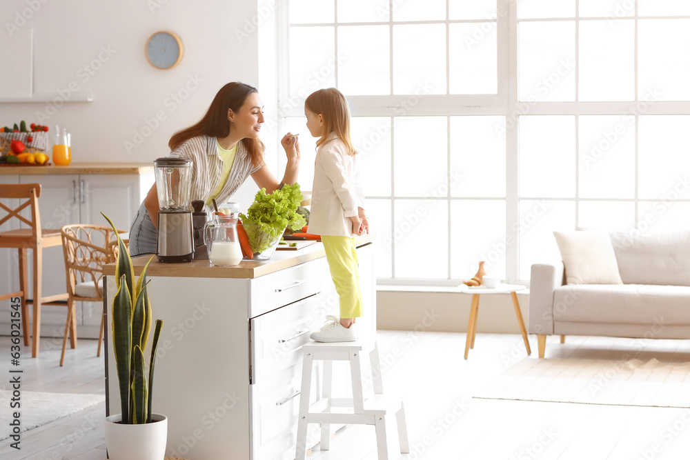 Little girl with her mother cooking healthy salad in kitchen