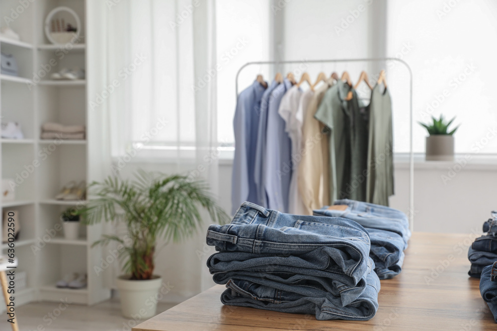 Table with stylish jeans pants in modern boutique, closeup