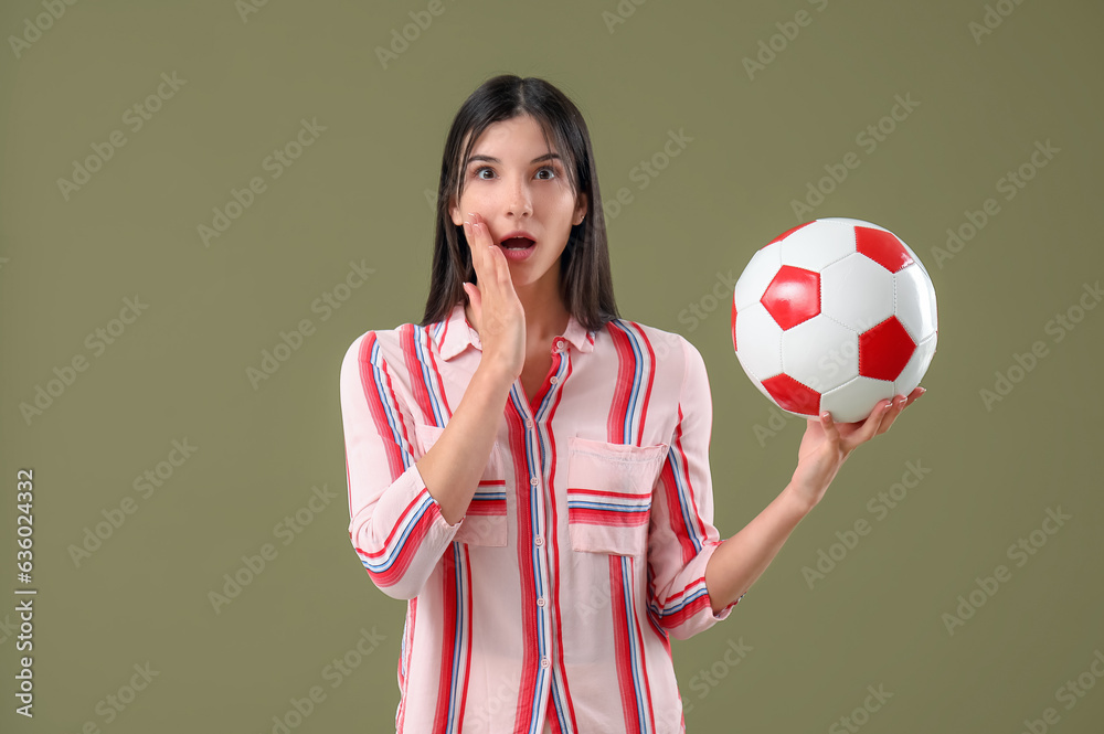 Surprised young woman with soccer ball on color background